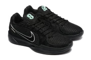 Three-quarter view of the black sneaker pair showing black laces, textured uppers, white side logos, and mint-green tongue graphics.