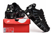 Black Nike Shox TL sneakers with white Swooshes displayed beside a Nike shoe box; the box label shows sample sizes.