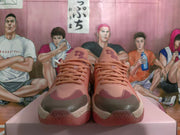 Front view of pink lace-up sneakers with dark contrasting toe accents.