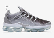 Side profile of the Nike Air VaporMax Plus sneaker in grey, black, and white