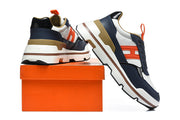 Navy, white, and orange Hermès sneakers displayed with an orange shoe box.