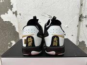 Rear view of white and black Nike basketball shoes with gold heel accents and black, speckled midsoles.
