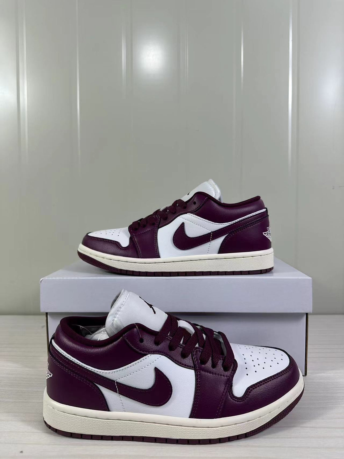 Pair of burgundy and white low-top Jordan sneakers displayed on a shoebox.