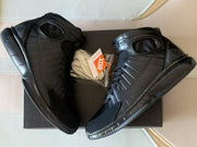 Black high-top shoes displayed with a spare set of light-colored laces.