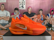 Side view of an orange Nike sneaker showing the white-and-orange Swoosh, layered upper panels, and visible ZOOMX marking near the midsole.