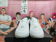 Front view of white Nike basketball sneakers showing lace-up fronts, black collar lining, and small black Swoosh details.