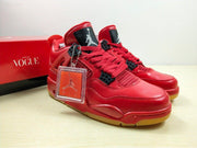 Angled front view of the red sneaker pair with red laces, black accents, gum-colored outsoles, and a presentation box.