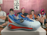 Side profile of a blue sneaker showing gray textured panels, red midsole accents, and a decorative circular emblem.