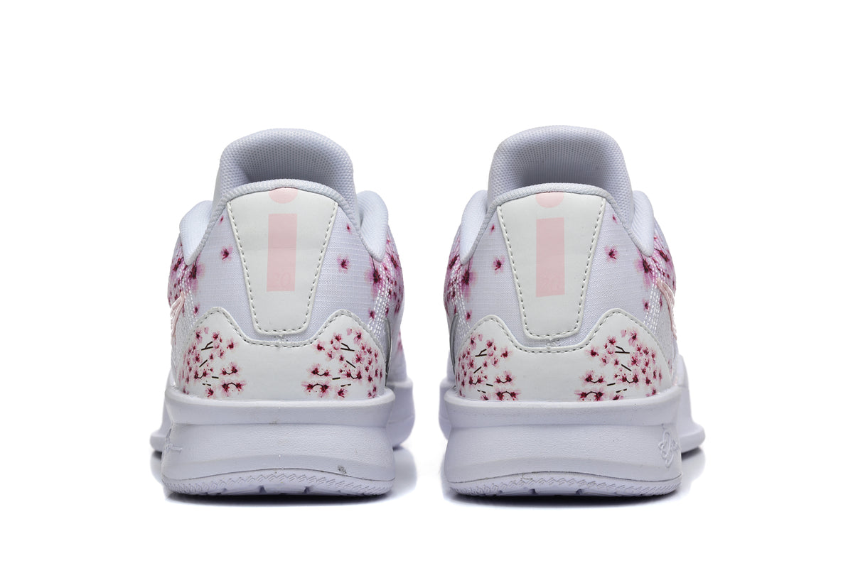 Rear view of white low-top Nike basketball shoes with pink floral graphics on the heels.