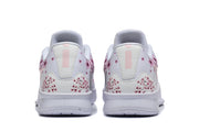 Rear view of white low-top Nike basketball shoes with pink floral graphics on the heels.