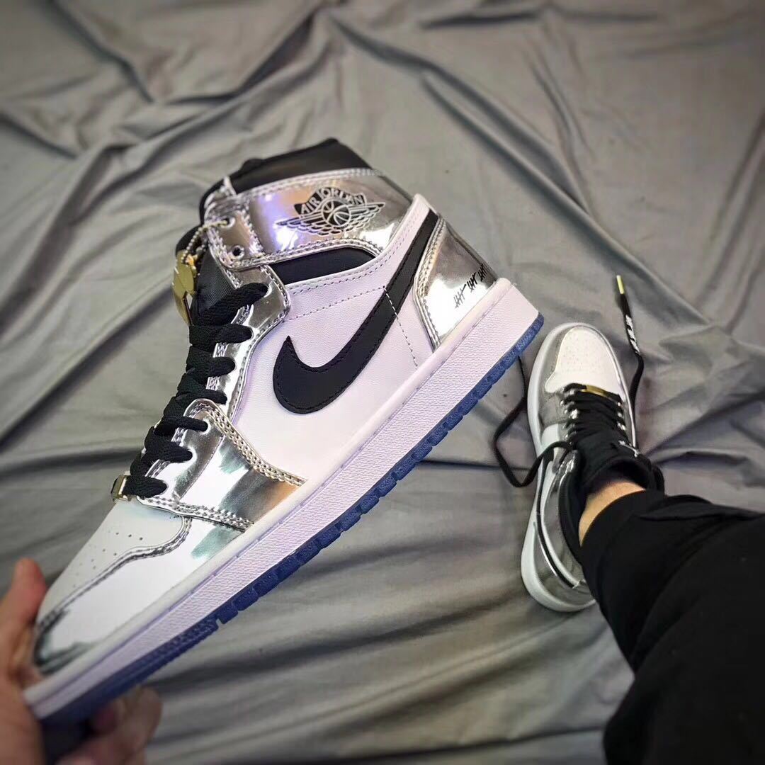 Close-up side view of a white and silver Jordan high-top sneaker with black Swoosh and blue outsole.