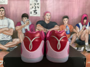 Rear view of pink basketball shoes with red heel panels, pale pink details, and light-colored soles.