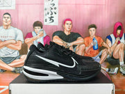 Side profile of a black basketball shoe with a white Swoosh-style detail and contrasting heel accent.