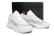 Pair of white-and-silver Nike A'ja Wilson 1 shoes displayed in front of a black shoebox.