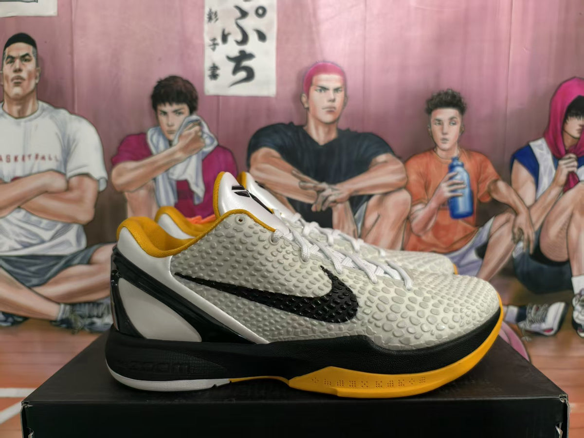 Side view of white, black, and yellow Nike Kobe basketball shoes