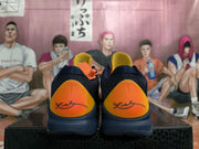 Rear view of navy basketball sneakers with bright yellow-orange heel panels and dark soles, displayed against an illustrated basketball-themed backdrop.