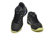 Pair of black Nike Kobe basketball shoes with gray speckled tongue panels and volt-colored outsole edges.