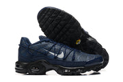 Side and outsole view of navy Nike Air Max Plus sneakers with patterned uppers and black sculpted soles.