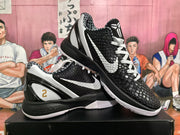 Angled view of paired black and white basketball sneakers showing the textured upper, white Swoosh, and patterned collar lining.