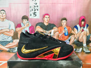 Side view of black Nike basketball sneakers with a gold Swoosh, red outsole, and angular gold-and-red accents