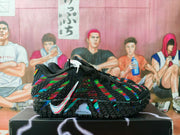 Side view of black Nike sneakers with multicolor patterned panels, a white Nike Swoosh, textured outsole, and ZoomX lettering.