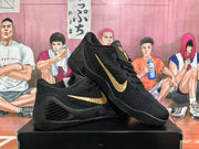 Angled view of black basketball sneakers with gold Swooshes and textured side panels.