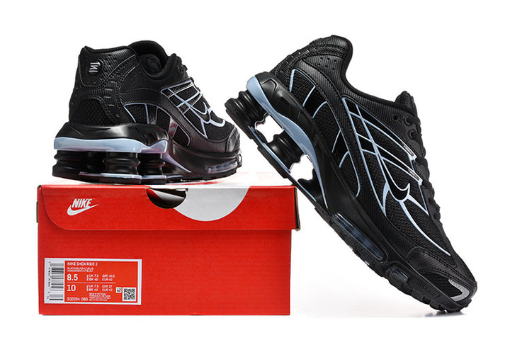 Black Nike Shox R4 sneakers with light blue details displayed on a red shoe box.