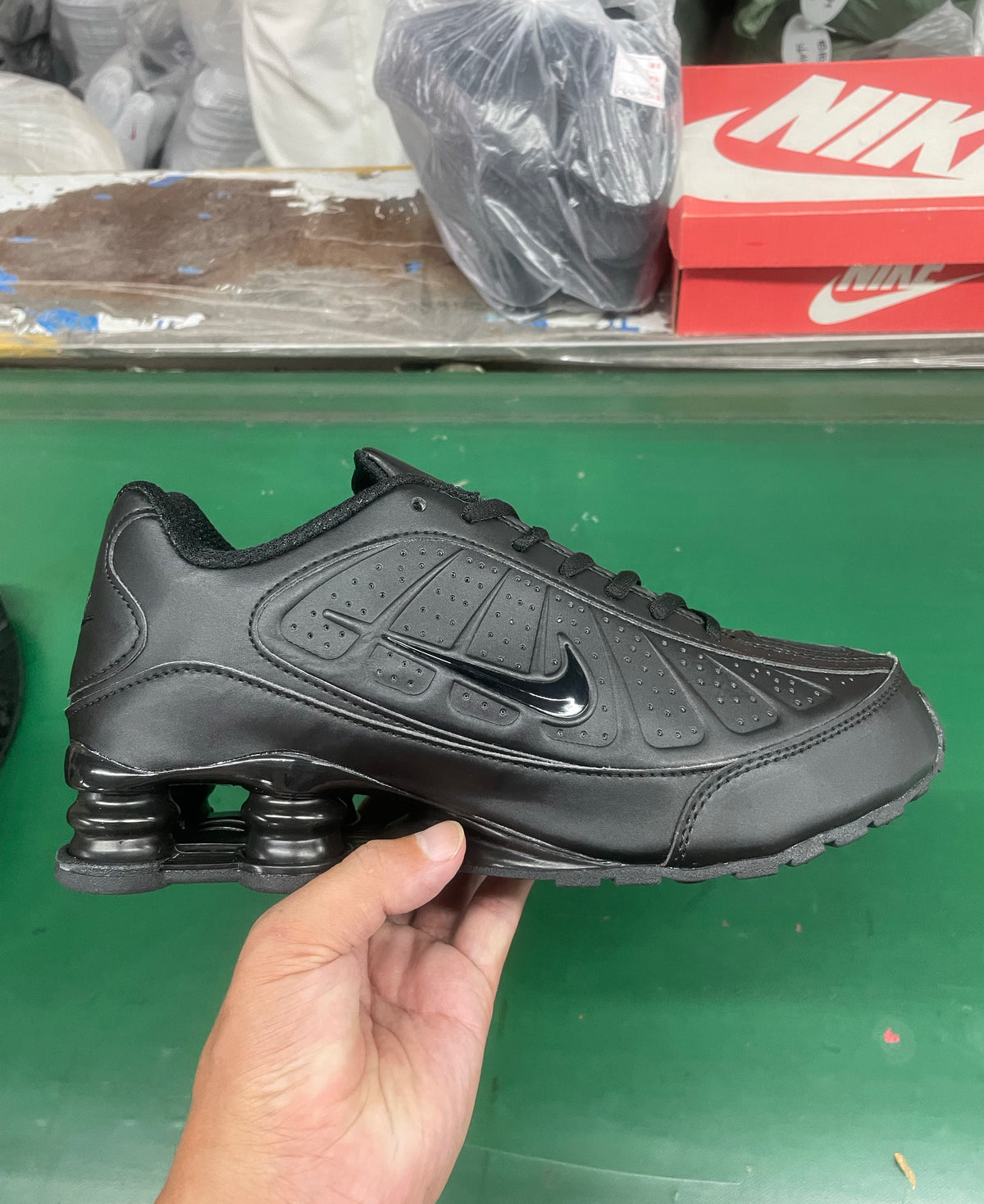 Black Nike low-top sneaker shown from the side, with perforated panels, a Swoosh and spring-like heel columns.