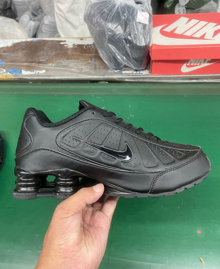 Black Nike low-top sneaker shown from the side, with perforated panels, a Swoosh and spring-like heel columns.
