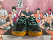 Front view showing green laces, black perforated panels, and orange outsole details.