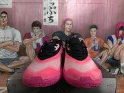 Front view of the black and pink sneakers showing the laces, toe boxes, and layered pink soles.