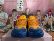 Front view showing orange-toned laces, blue toe accents, and tongue details