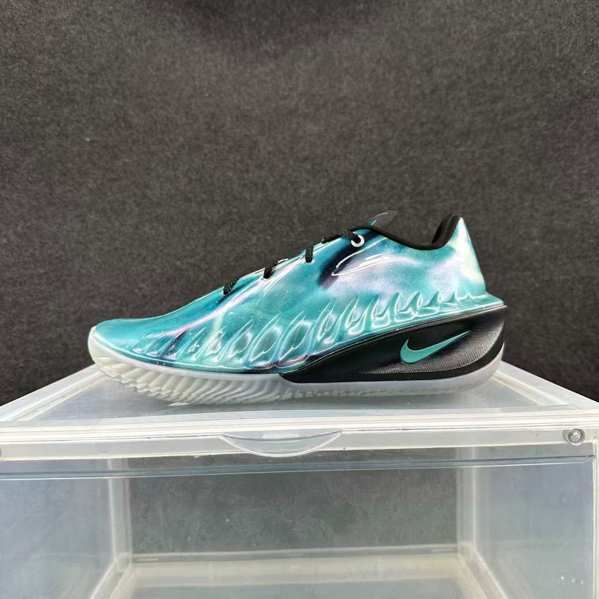 Side view of an iridescent blue-purple basketball shoe with black laces and turquoise Swoosh accent
