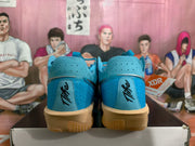 Rear view of blue Nike basketball sneakers showing perforated heel panels, black script-style heel details, and gum-colored outsoles.