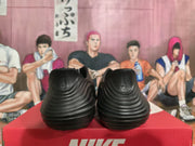 Rear view of black Nike sneakers showing layered heel detailing and Nike logos, displayed on a red Nike shoebox.