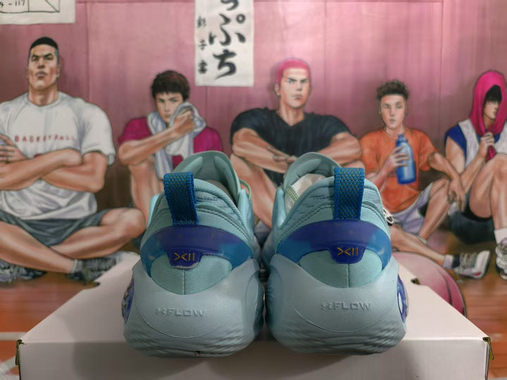 Rear view of light blue basketball sneakers showing darker blue heel panels, pull tabs, and visible XII markings.