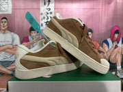 Pair of brown PUMA low-top sneakers with cream-colored accents, shown from the side