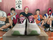 Front view showing grey-white perforated uppers, pink laces, black accents and pale green toe details.