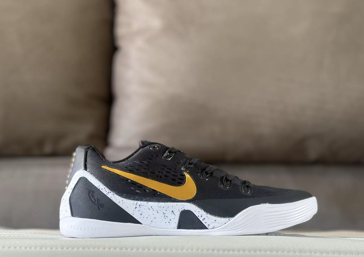 Side view of black Nike Kobe 9 sneakers with a gold Swoosh and white speckled side panel.