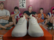 Front view of the white Nike sneakers with white laces, red tongue details, and blue side accents partially visible.