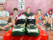 Front view of the pair showing military green camouflage toe boxes, black laces, white tongues, and textured black outsoles.