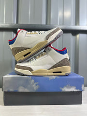 Pair of Jordan Air Jordan 3 Retro sneakers displayed on a blue-and-cloud shoebox.