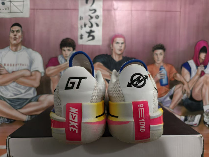 Rear view of white and gray Nike GT sneakers showing GT heel marks, blue collars, and pink and yellow heel accents.