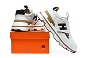 White and black sneakers displayed beside an orange shoebox.