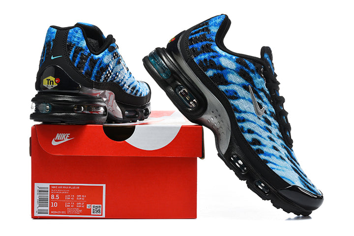 Pair of blue patterned Nike Air Max Plus VII sneakers displayed with a red Nike shoe box; box label shows sample sizes.