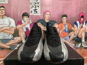 Front view of black and silver Adidas basketball sneakers with black laces, mesh-style uppers, and blue tongue logos.