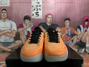 Front view of orange-toned Jordan sneakers with black laces, black tongues, and perforated toe boxes.