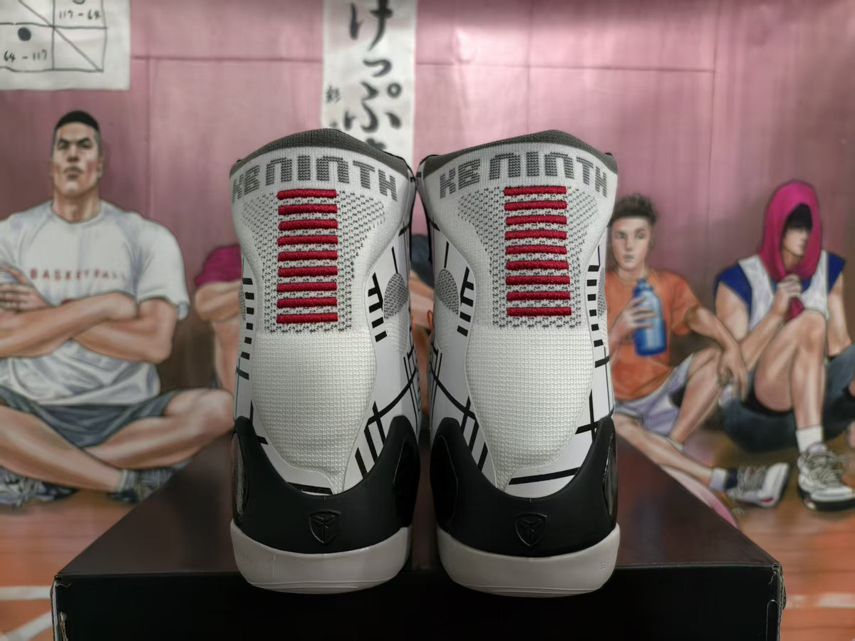 Rear view of the white and black high-top basketball sneakers showing red tongue detailing and heel graphics.