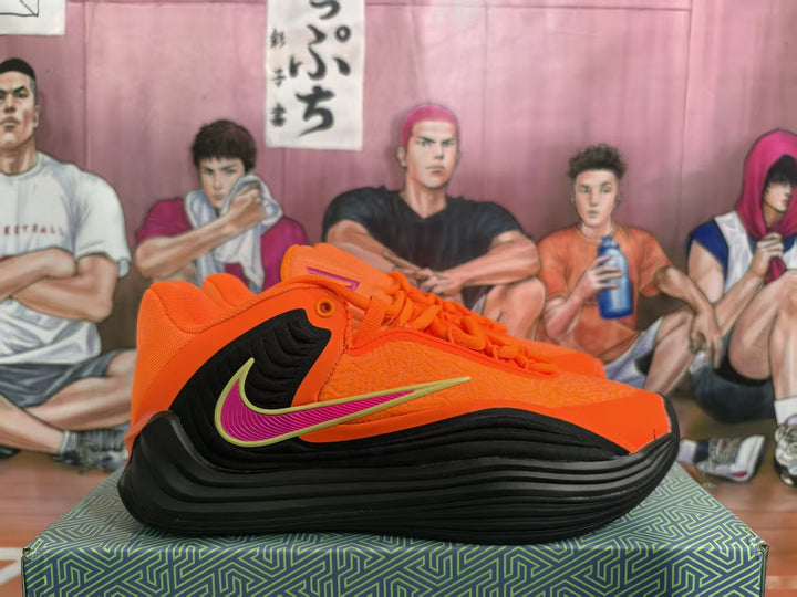 Side view of orange and black basketball sneakers with contrasting swoosh details and a layered black sole.