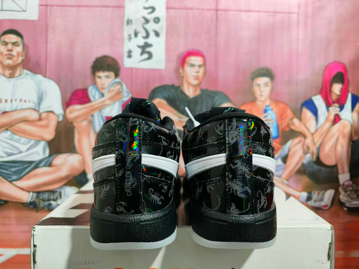 Rear view of black low-top sneakers showing scorpion graphics, reflective accents, white heel stripes, and contrasting soles.